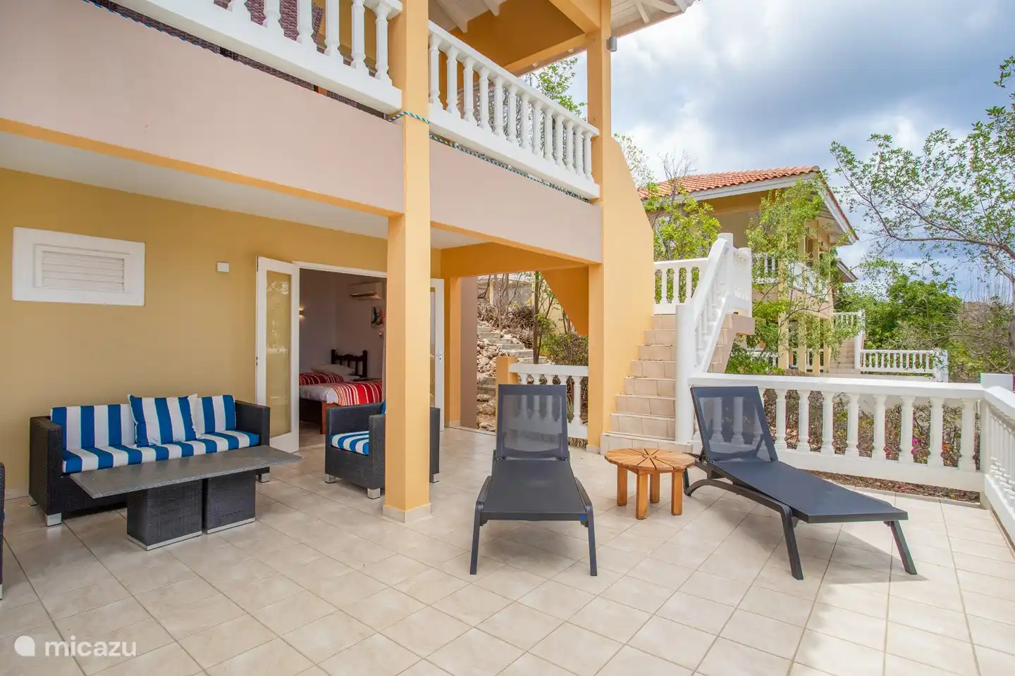 Shaded pool deck with comfortable loungers and sofas and the patio doors of the downstairs bedrooms.