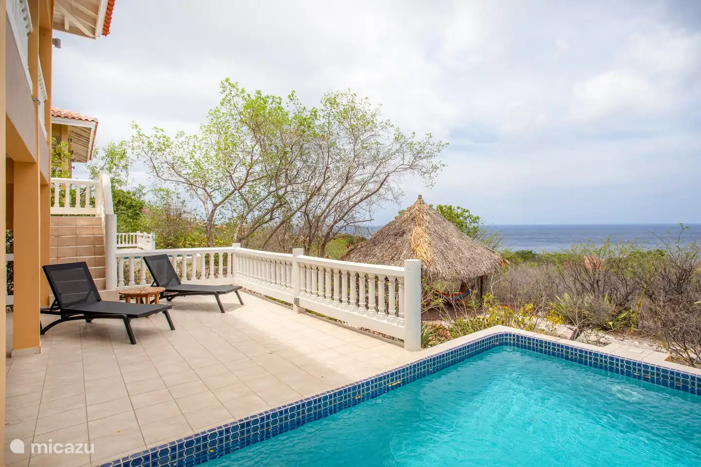 Shaded pool deck with comfortable loungers and sofas