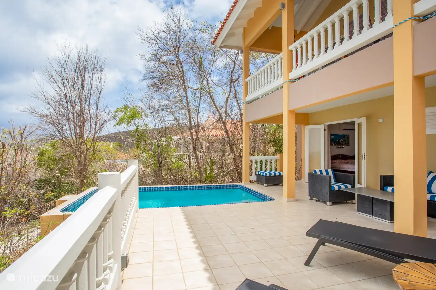 Shaded pool deck with comfortable loungers and sofas