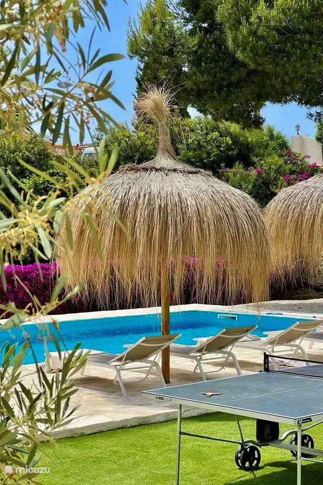 Im mediterranen Garten befindet sich ein großer privater Swimmingpool, der von Sonnenliegen und Sonnenschirmen umgeben ist.
