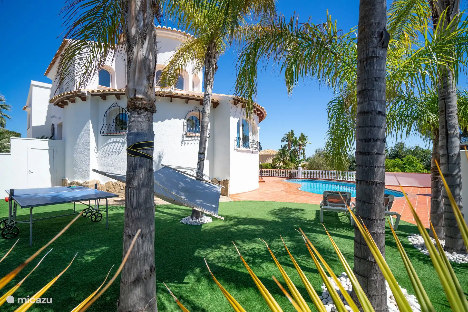 El jardín mediterráneo de Villa Rosana cuenta con palmeras, una hamaca y una piscina privada