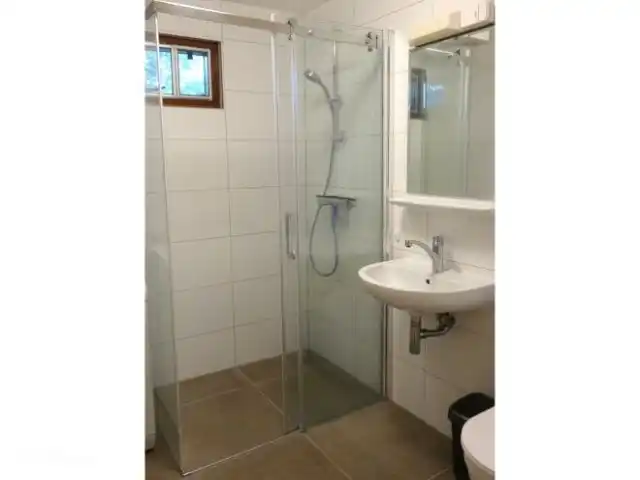 De badkamer uit 2022 met inloopdouche en wasmachine.