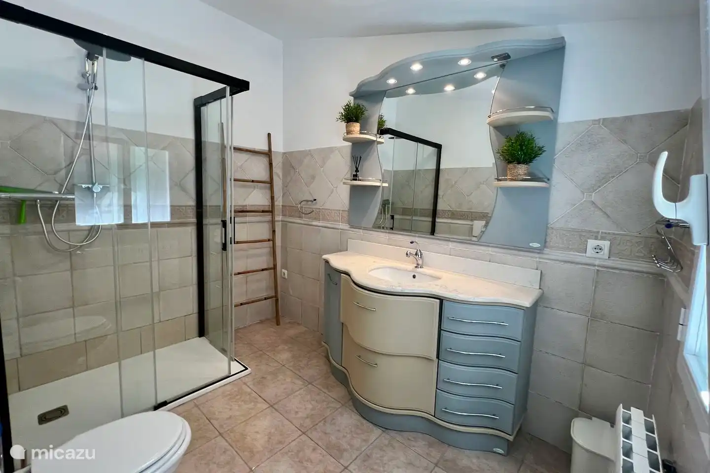 Ensuite badkamer van de hoofdslaapkamer met regendouche, wastafel en toilet.