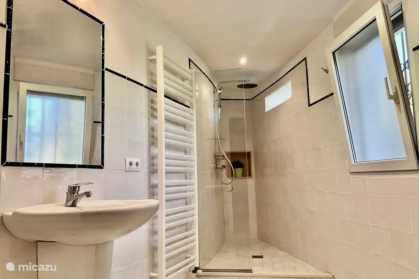 Ensuite badkamer van tweede slaapkamer met regendouche, wastafel en toilet.