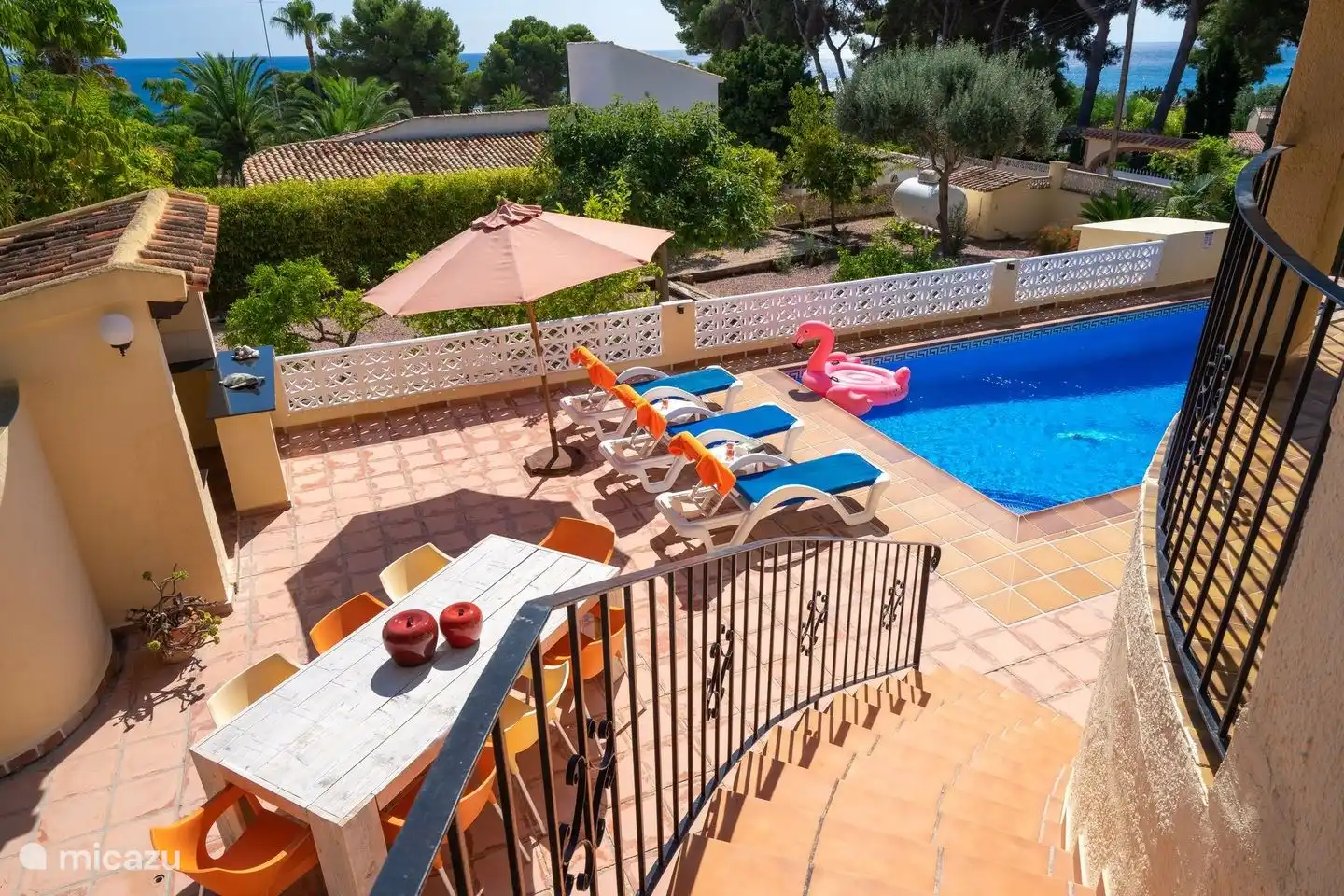 Am privaten Pool steht ein großer Esstisch