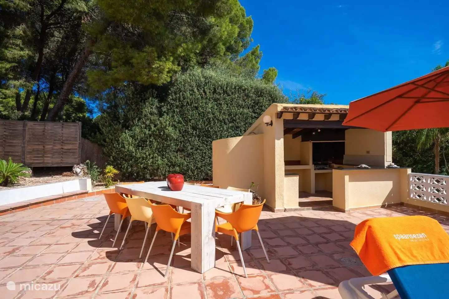 Im Garten der Villa Patricia steht ein großer Esstisch neben dem Grill