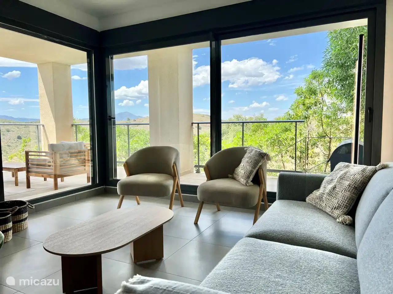 Modern ingerichte woonkamer met bank, relaxstoelen, televisie met Chromecast en met uitzicht op de bergen