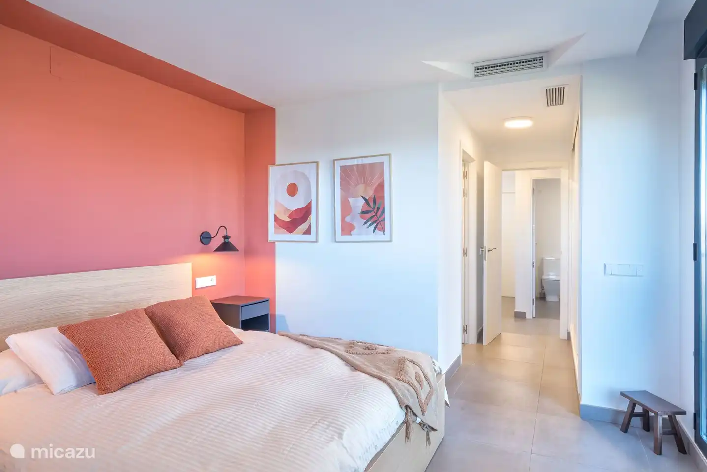 Slaapkamer met tweepersoonsbed, en-suite badkamer en terras met uitzicht op de bergen.