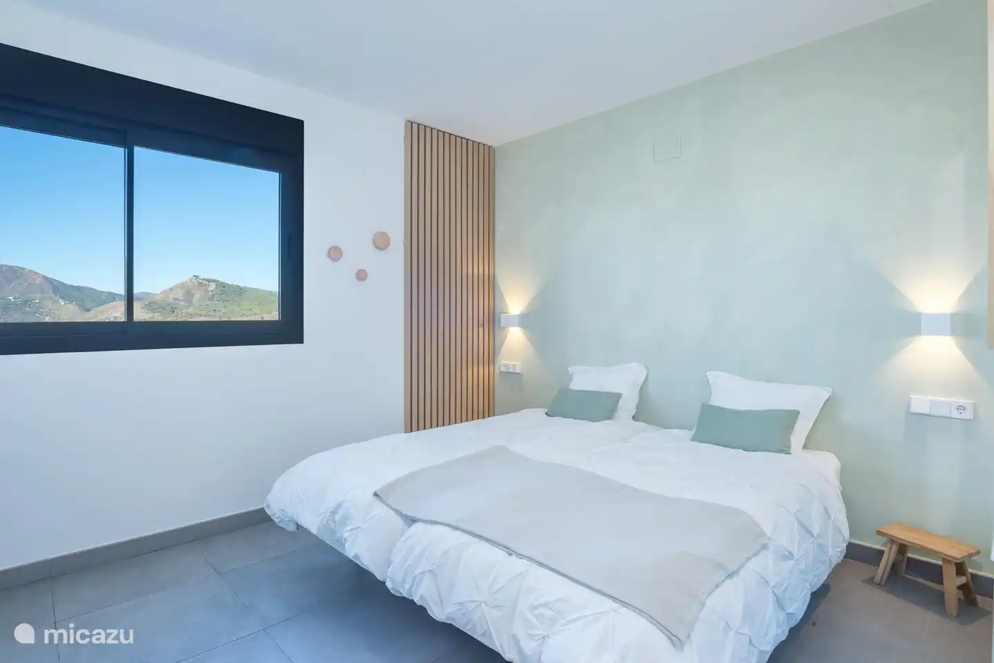 Slaapkamer met twee éénpersoonsbedden, inbouwkast en uitzicht op de bergen.