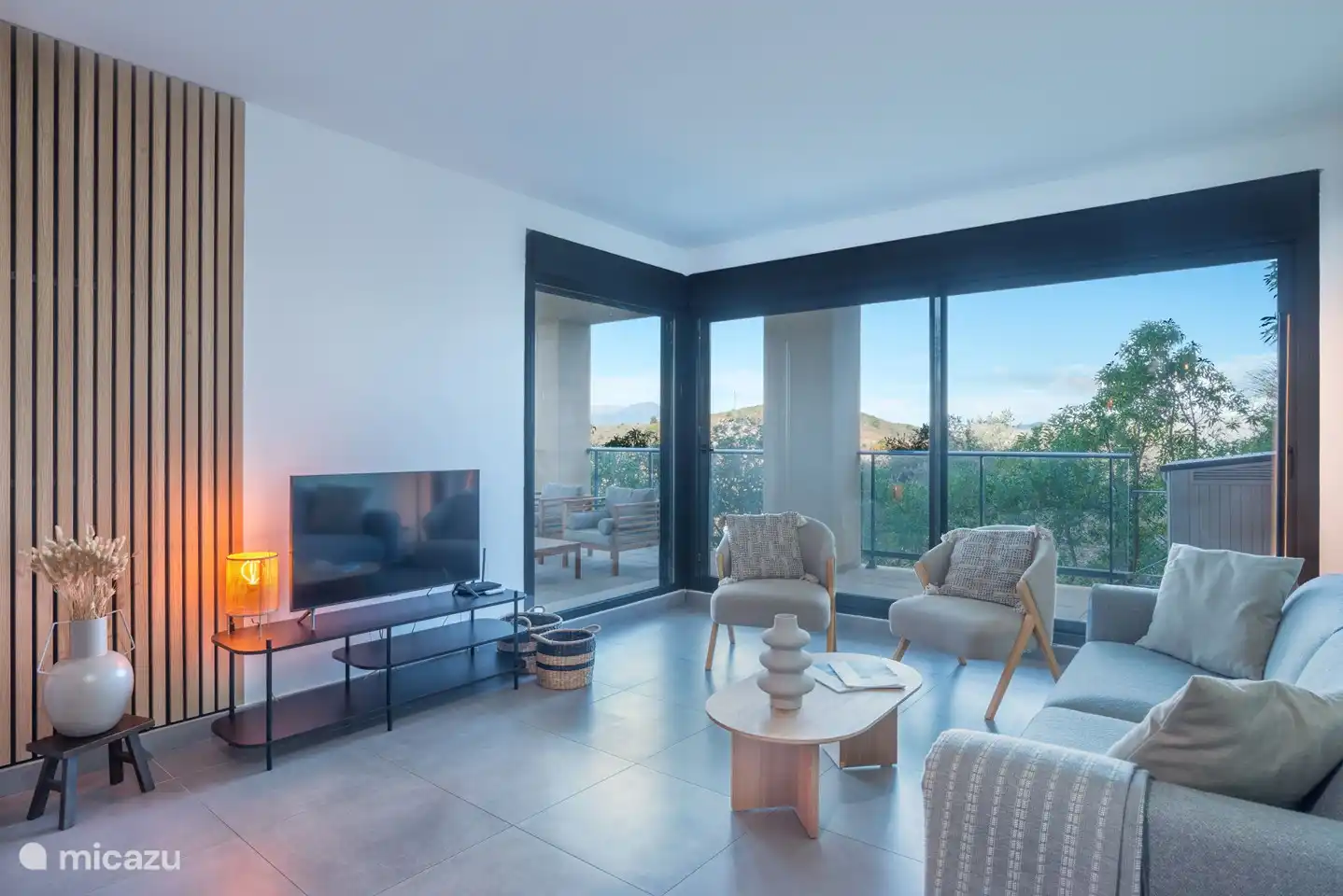 Modern ingerichte woonkamer met bank, relaxstoelen, televisie met Chromecast en met uitzicht op de bergen