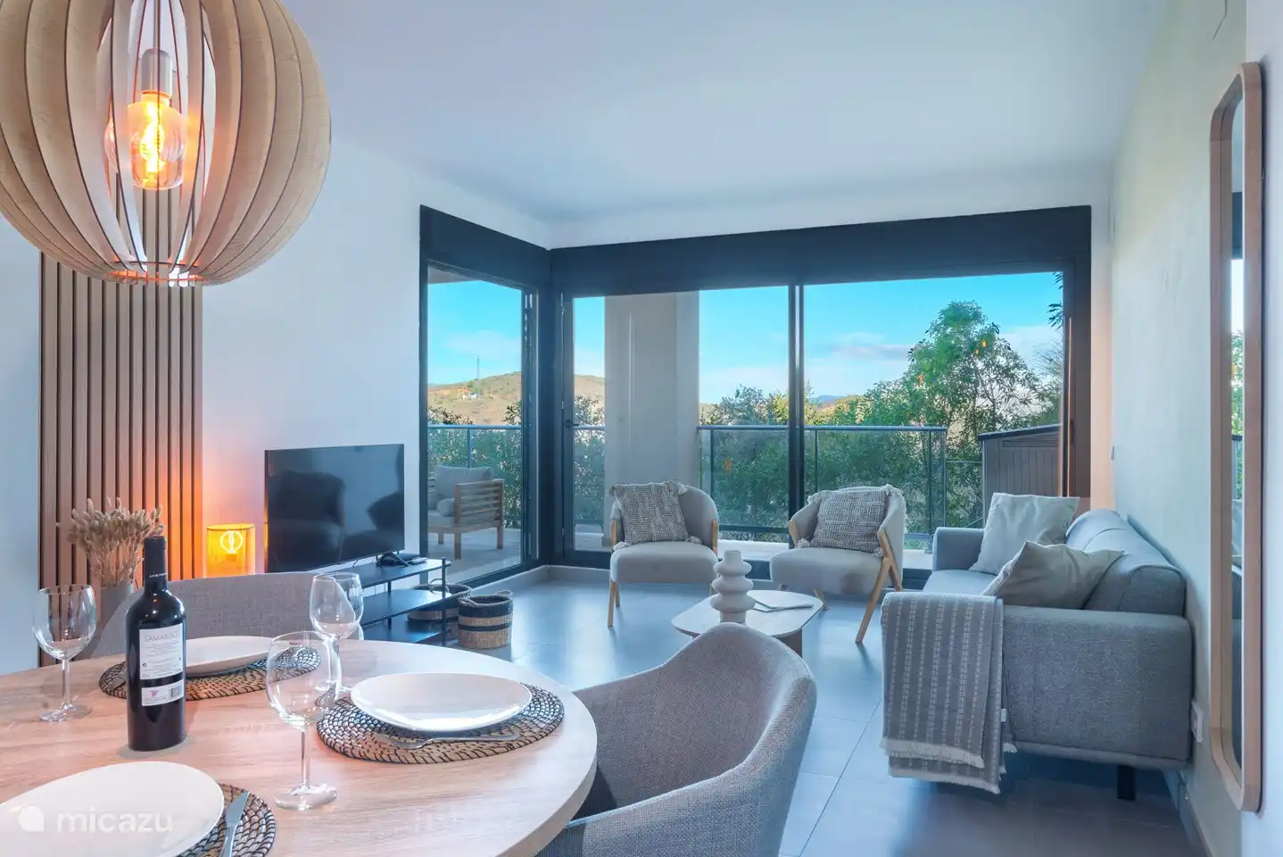 Modern ingerichte woonkamer met bank, relaxstoelen, televisie met Chromecast en met uitzicht op de bergen