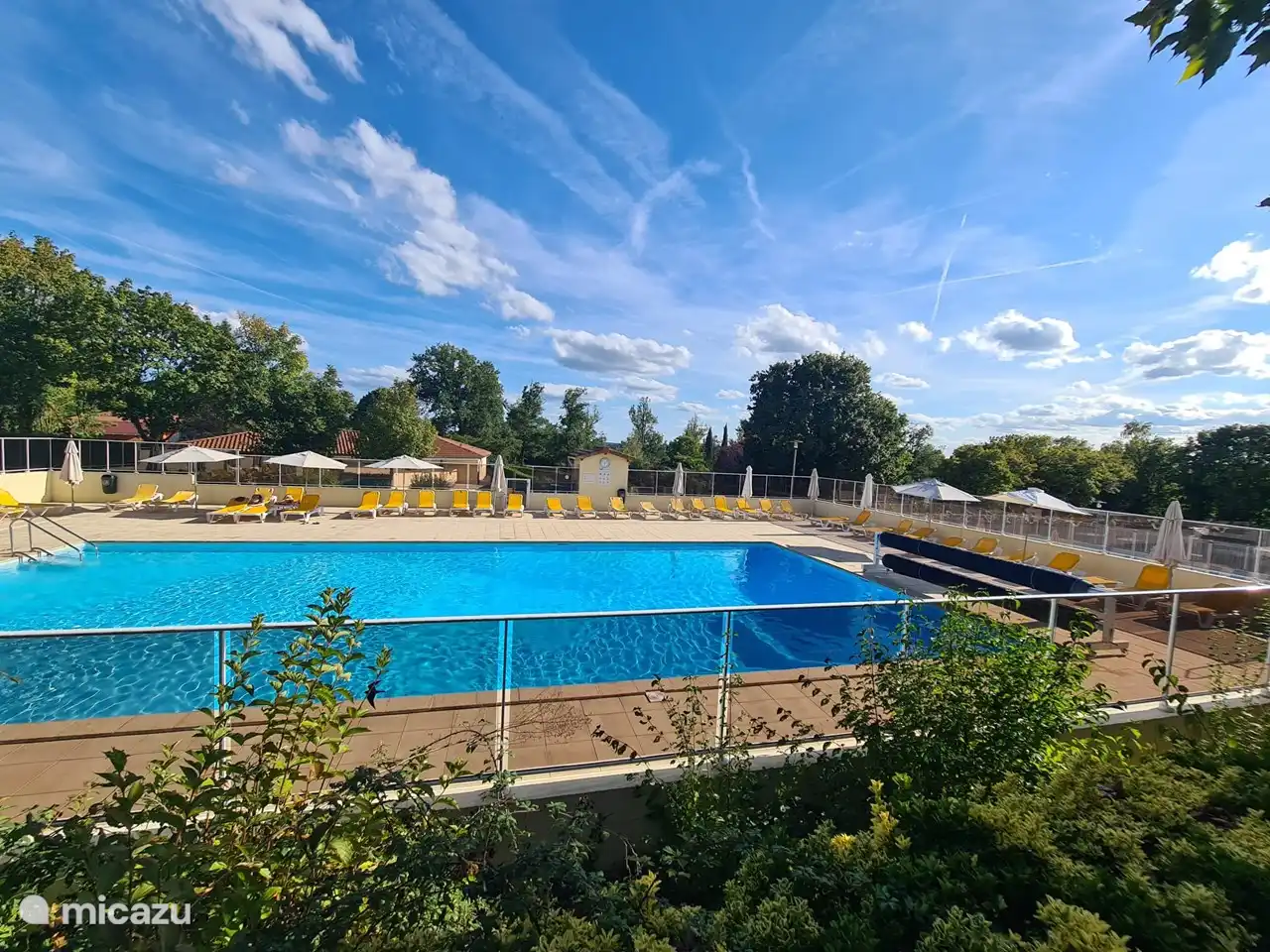 Großer Swimmingpool mit Sonnenliegen und Sonnenschirm