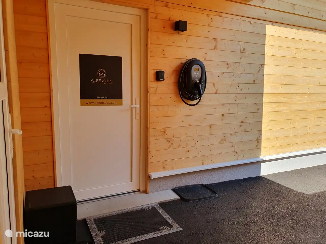 La entrada con el trastero a la izquierda y la caja fuerte de llaves y la estación de carga para coches eléctricos a la derecha.