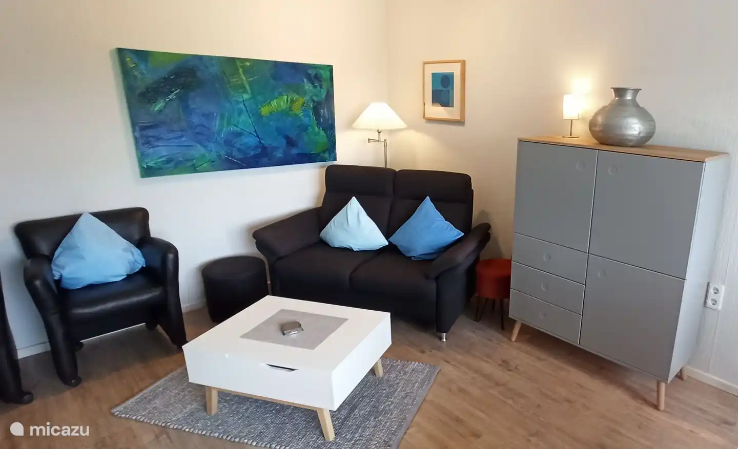 Wohnzimmer mit Doppelsitzer Couch und 2 Sesseln.