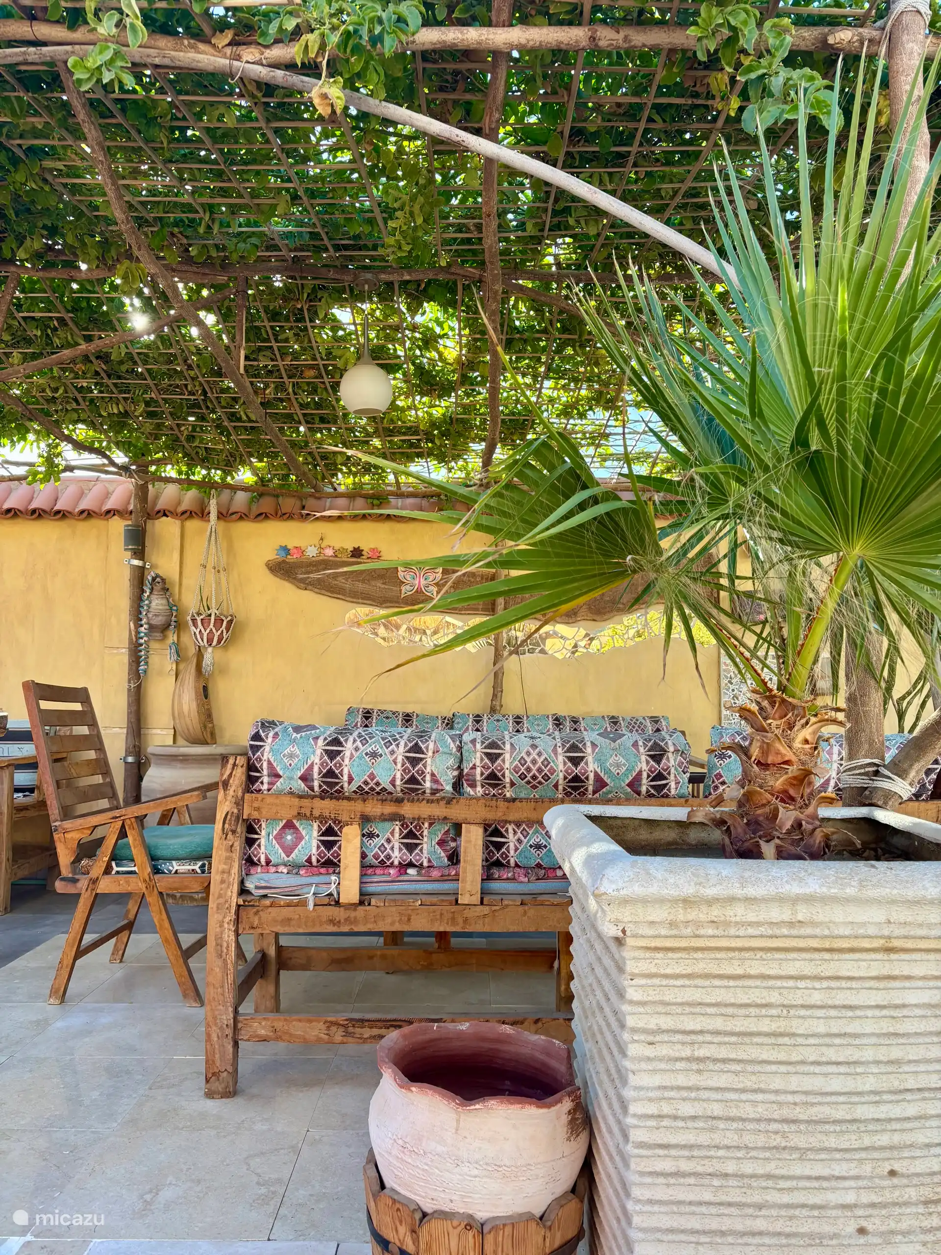 Gezellige zithoek onder schaduw dak van passievrucht 