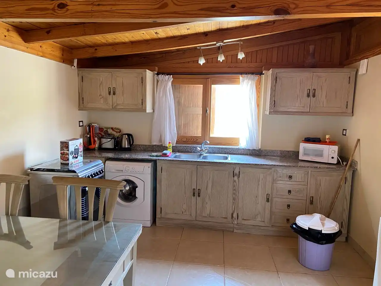 Kitchen with microwave, kettle, toaster, blender, washing machine, gas stove with oven.