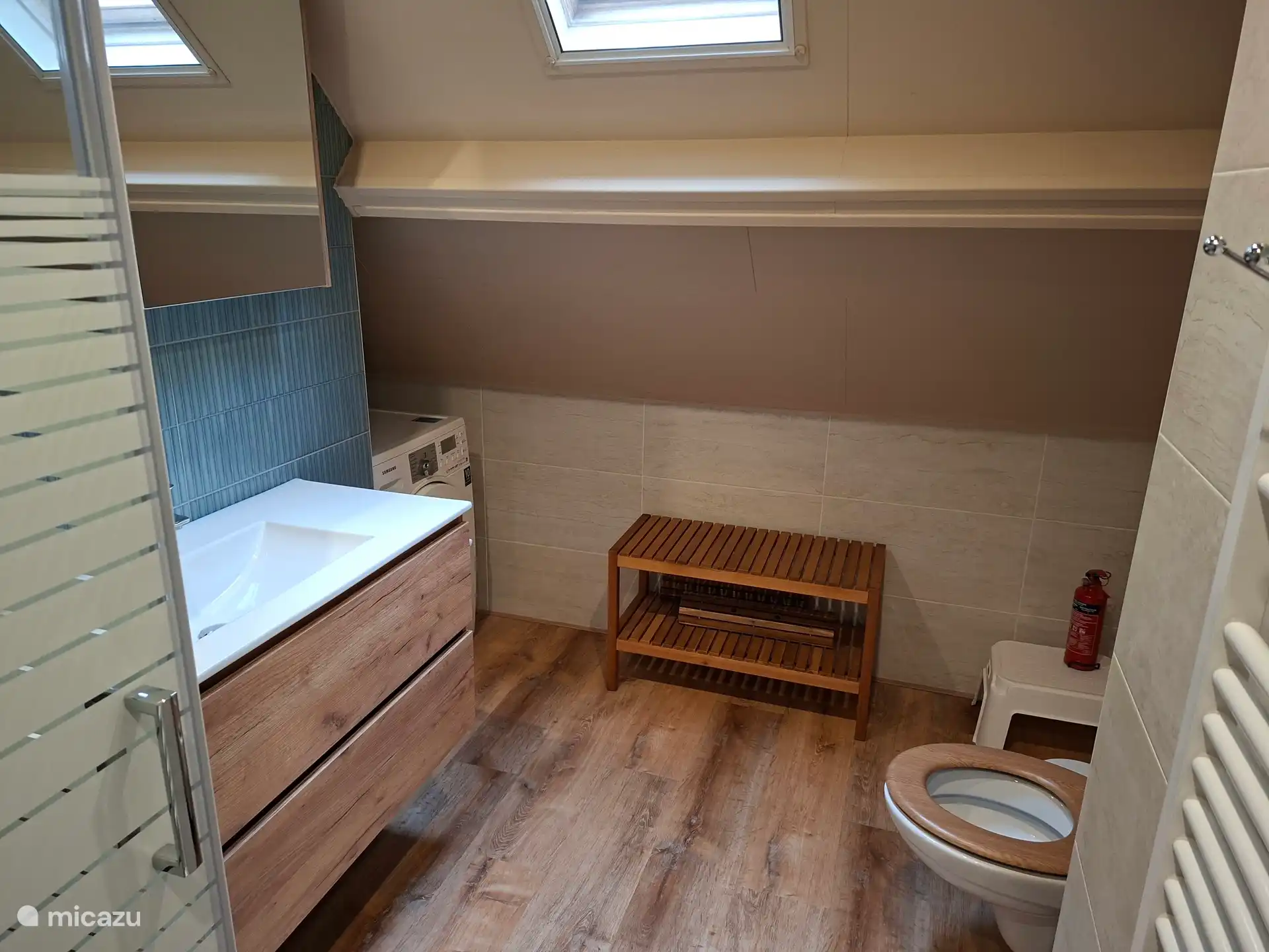 Badkamer met wastafelmeubel, toilet, douchecabine en wasmachine