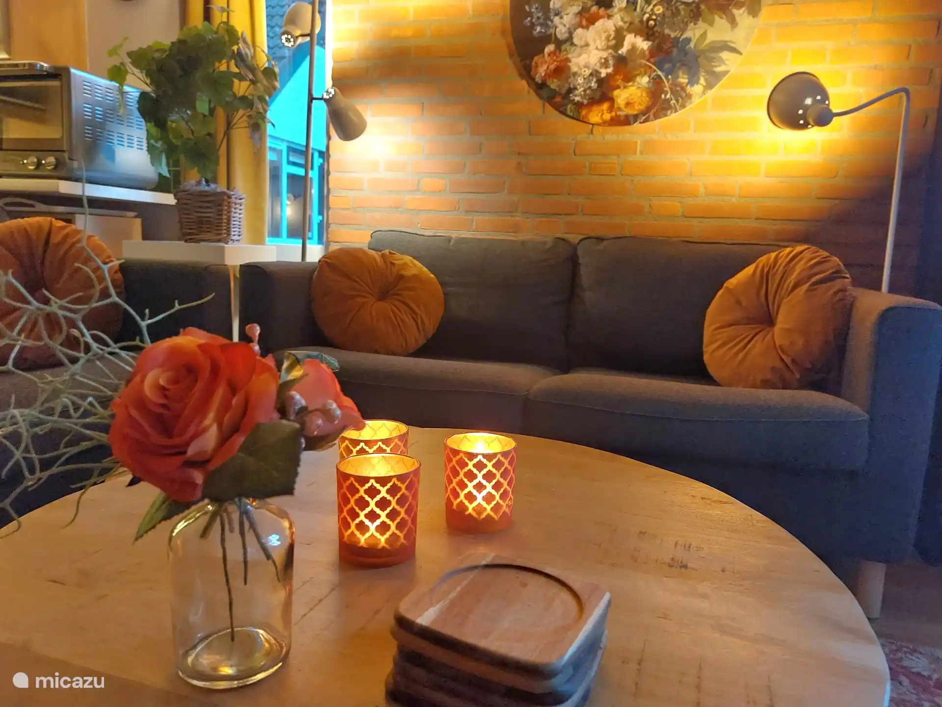 Sfeervol zitgedeelte met decoratie, kandelaars, zijdebloemen en een boekenkast met boeken en spelletjes