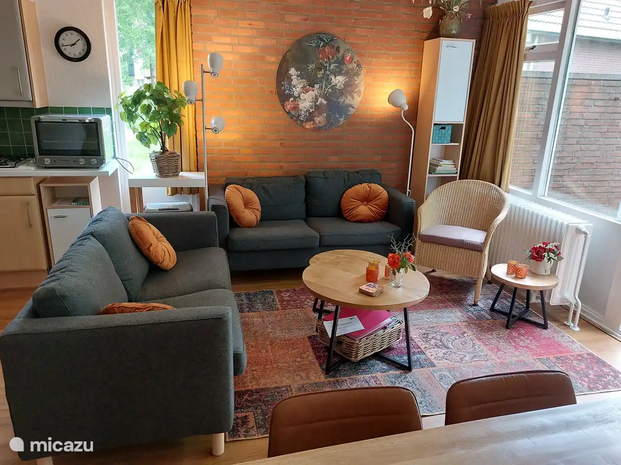 The living room with 2 nice sofas, an armchair and a bookcase with books, games, coloring books, etc.