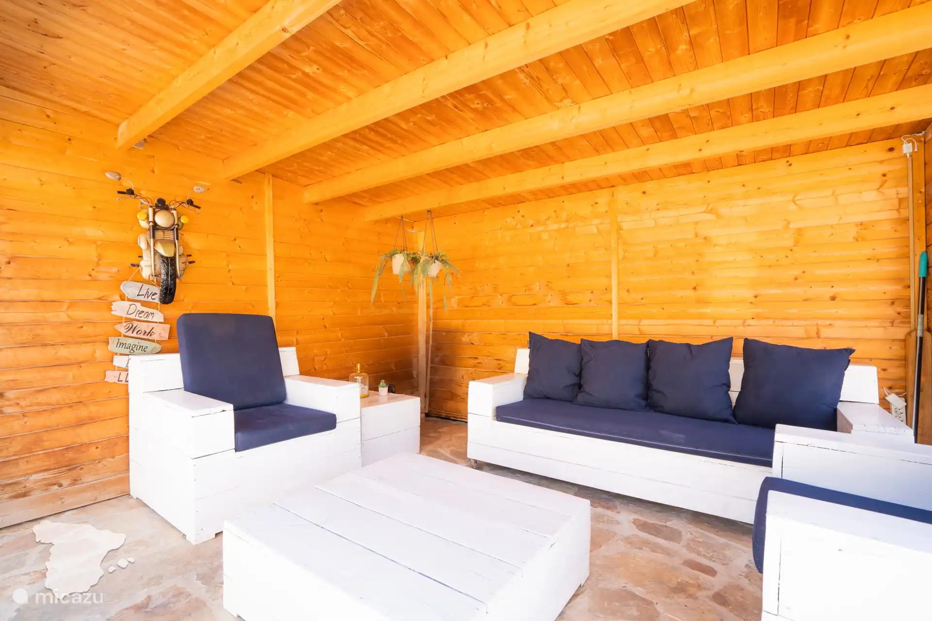 Sitzecke und dahinter ein Vordach mit Loungebereich