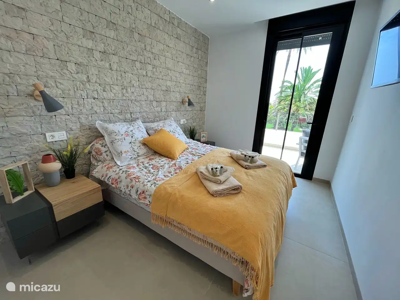 Dormitorio principal con baño adyacente. Equipado con aire acondicionado y vista a las palmeras.