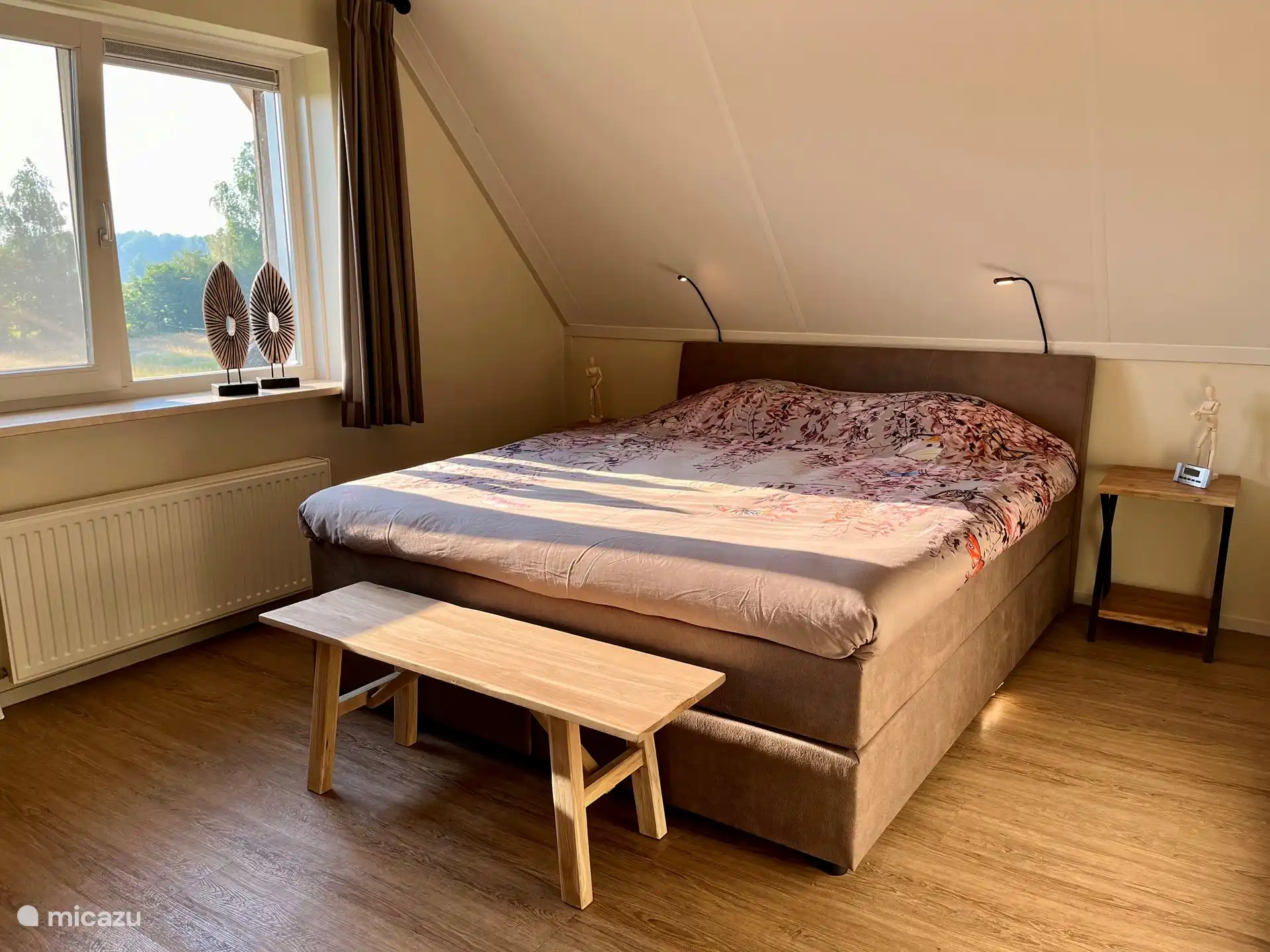 Hauptschlafzimmer mit großem Boxspringbett für 2 Personen 180x210, dimmbaren Leselampen, Innen-/Außenbeleuchtung, geräumigem Kleiderschrank mit Ganzkörperspiegel und Blick über die Wiese.
