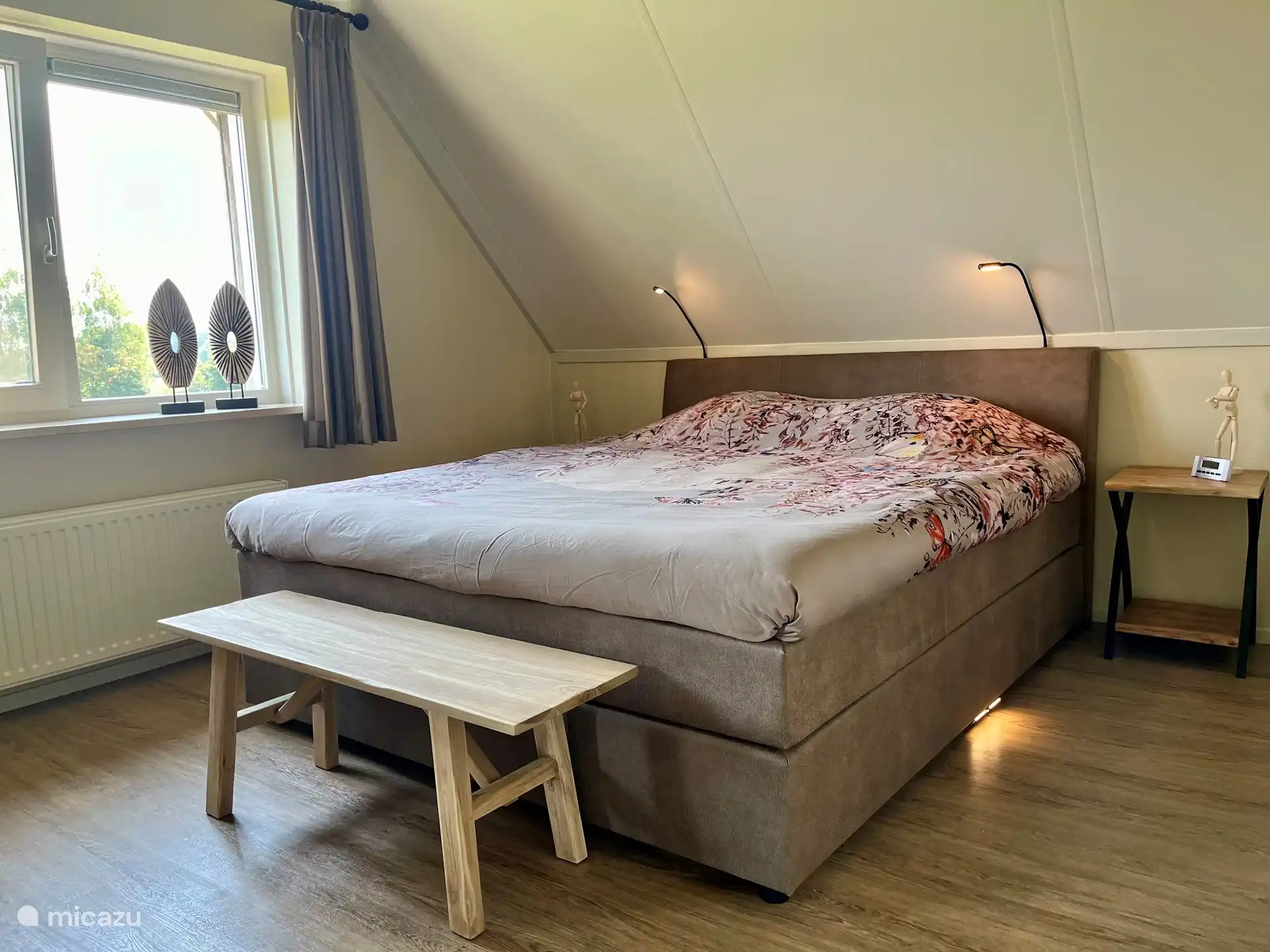 Hauptschlafzimmer mit großem Boxspringbett für 2 Personen 180x210, dimmbaren Leselampen, Innen-/Außenbeleuchtung, geräumigem Kleiderschrank mit Ganzkörperspiegel und Blick über die Wiese.