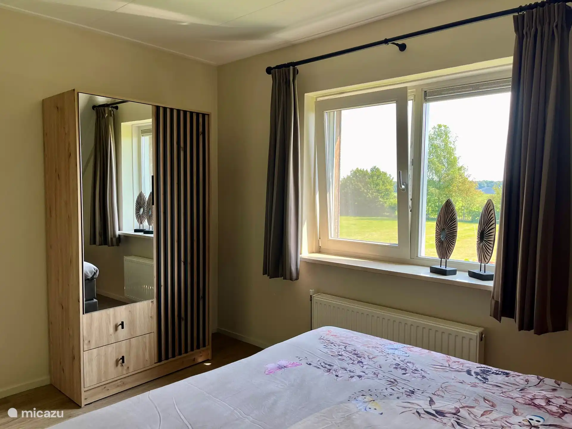 Hauptschlafzimmer mit großem Boxspringbett für 2 Personen 180x210, dimmbaren Leselampen, Innen-/Außenbeleuchtung, geräumigem Kleiderschrank mit Ganzkörperspiegel und Blick über die Wiese.