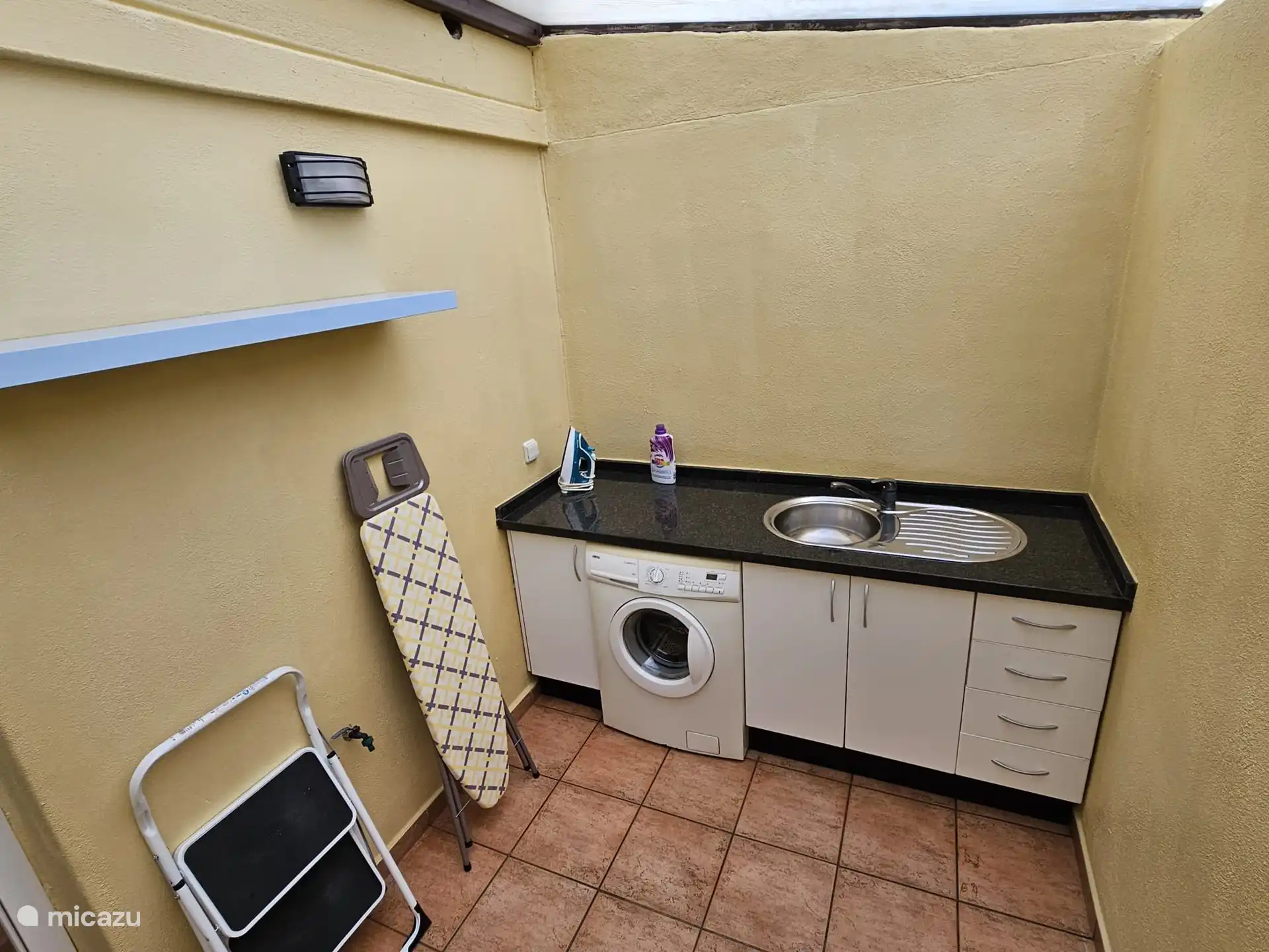 Hauswirtschaftsraum mit Waschmaschine, Bügelbrett und Bügeleisen