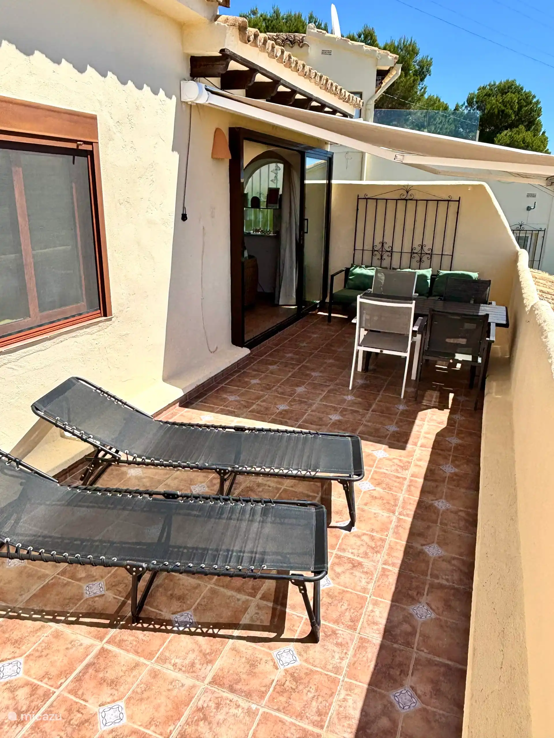 Balcony with luxury electric awning, terrace, bench and sunbeds.