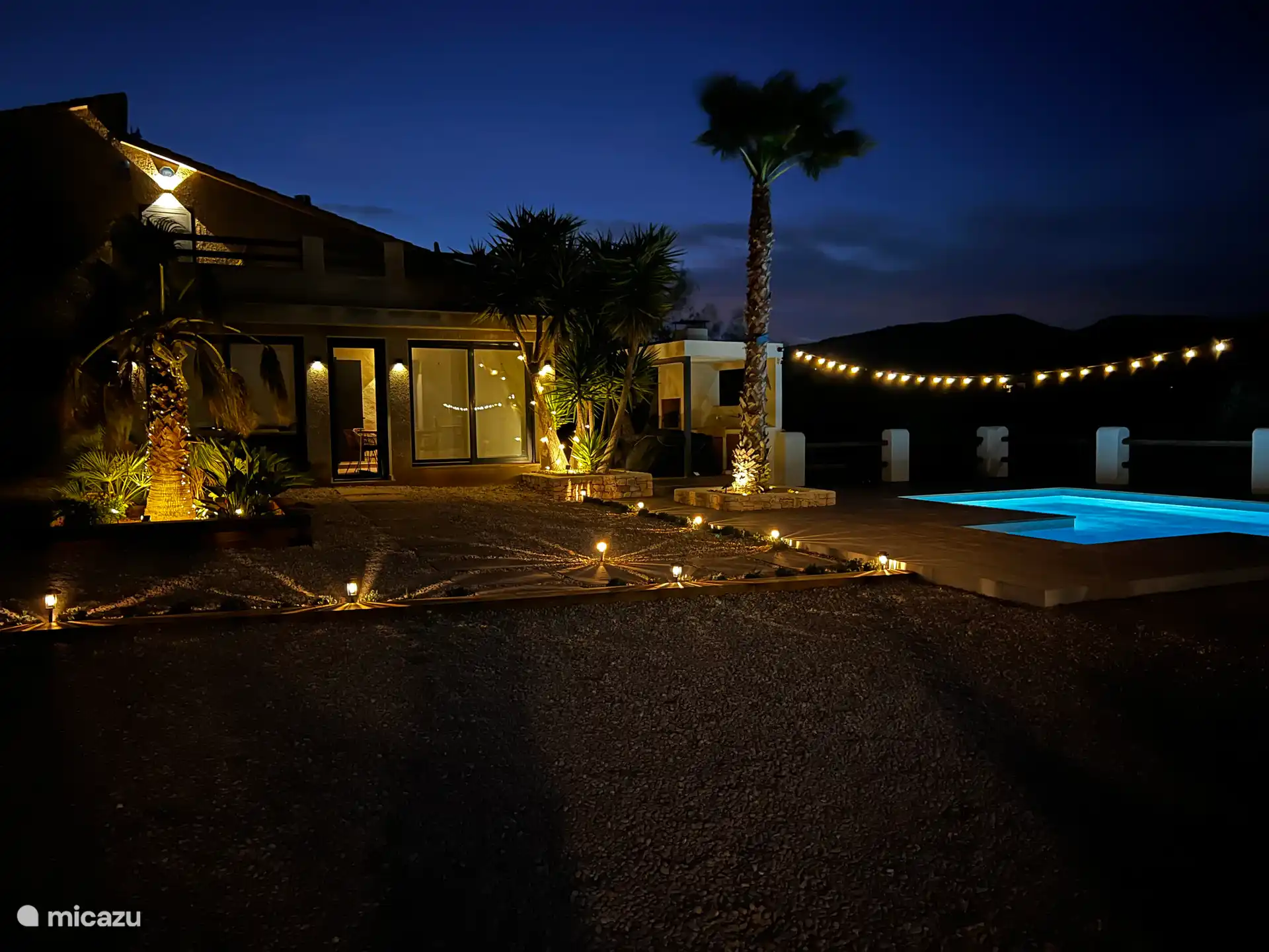 Het terrein beschikt over een gezellige kleine tuin met planten en palmbomen, wat zorgt voor een warme sfeer. Sfeerverlichting verbetert de ruimte 's nachts, perfect om te ontspannen.