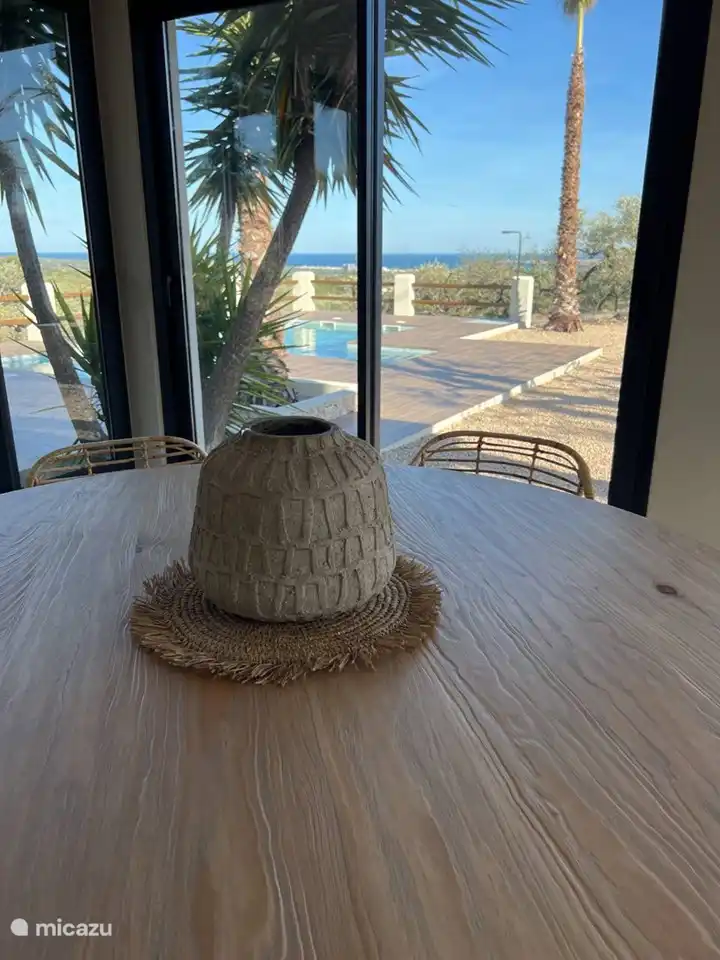 Ein bezaubernder Anblick entfaltet sich auf der Innenterrasse, die mit einem geräumigen Holztisch geschmückt ist. Mit atemberaubendem Blick auf den Garten und den Pool ist es ein idyllischer Ort, um bleibende Erinnerungen zu schaffen. Die perfekte Mischung aus Natur und Komfort lädt zu gemütlichen Zusammenkünften ein und umhüllt die Gäste in ein ruhiges und magisches Ambiente.