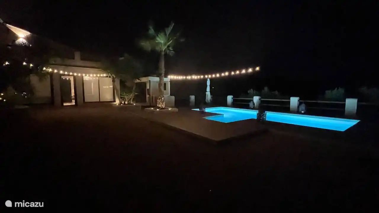 Unter dem mondbeschienenen Himmel steht unsere Villa elegant, mit dem glitzernden Pool davor und einer faszinierenden nächtlichen Oase.