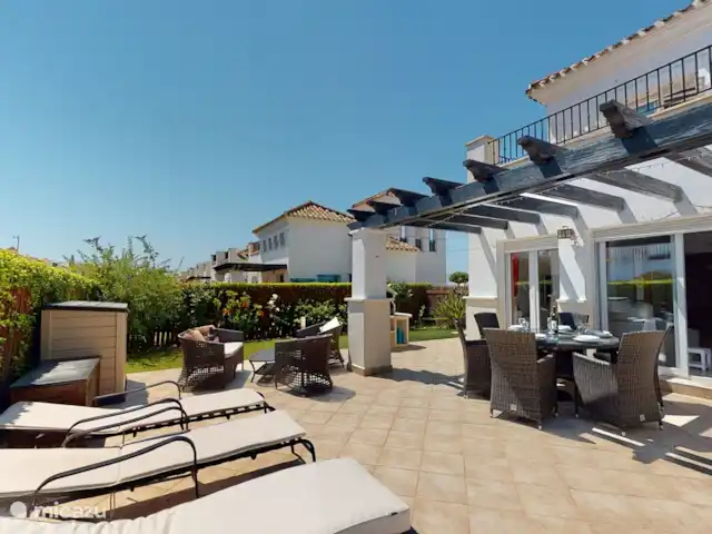 Casa Gofré | Espagne, Costa Cálida, Torre Pacheco - villa Terrasse derrière le salon avec 6 bains de soleil avec coussins, 6 chaises de salle à manger, table ronde avec plateau en verre, au milieu un plateau tournant en verre. barbecue. 2 bacs de jardin pour ranger les coussins de transat et de chaise.