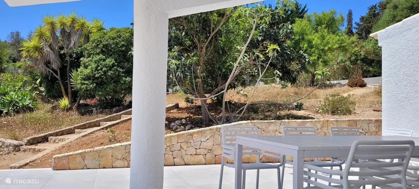 La terraza cerca de la sala de estar con vista al jardín y la piscina.