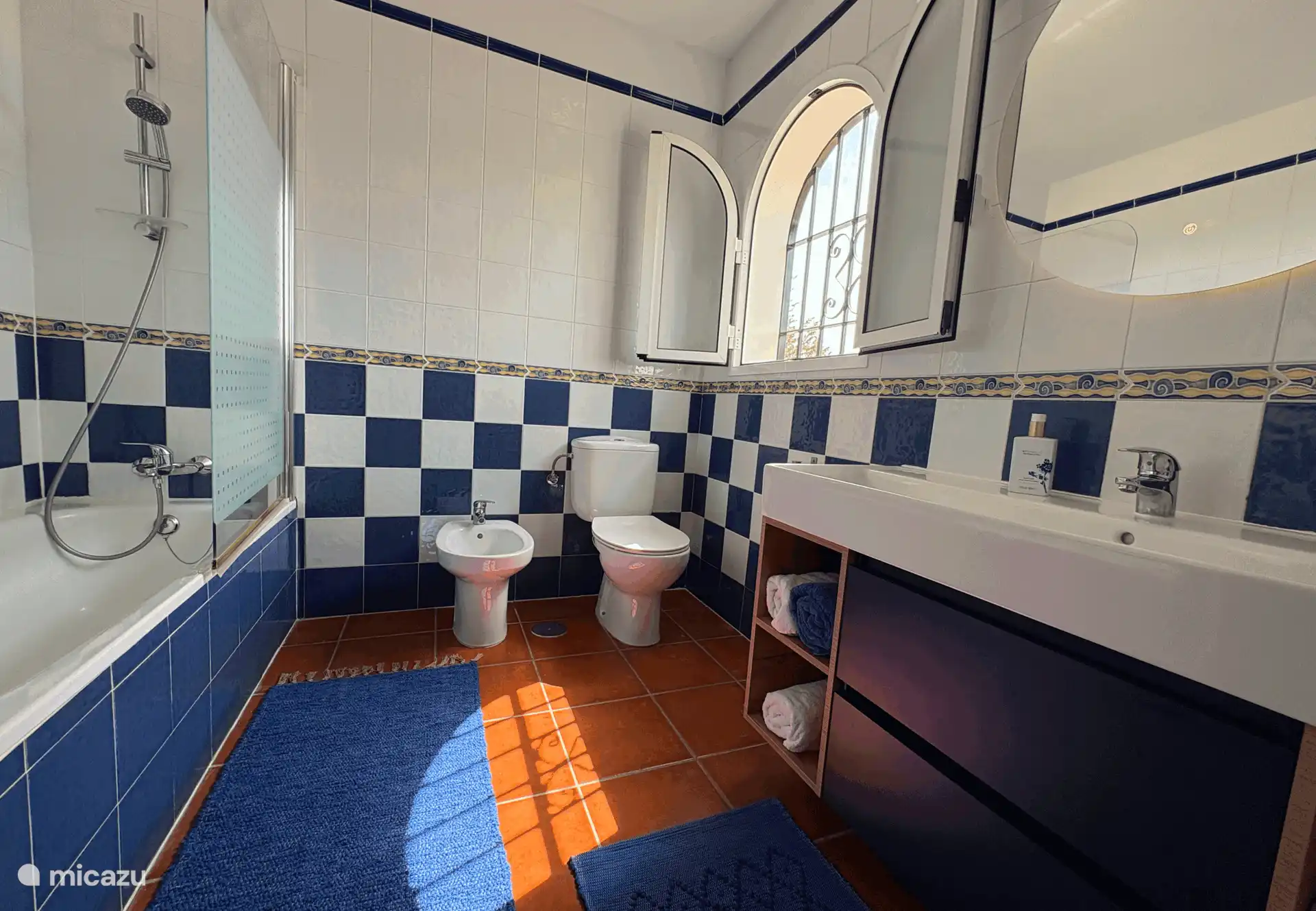 Met een bad met douche, toilet, wastafel.