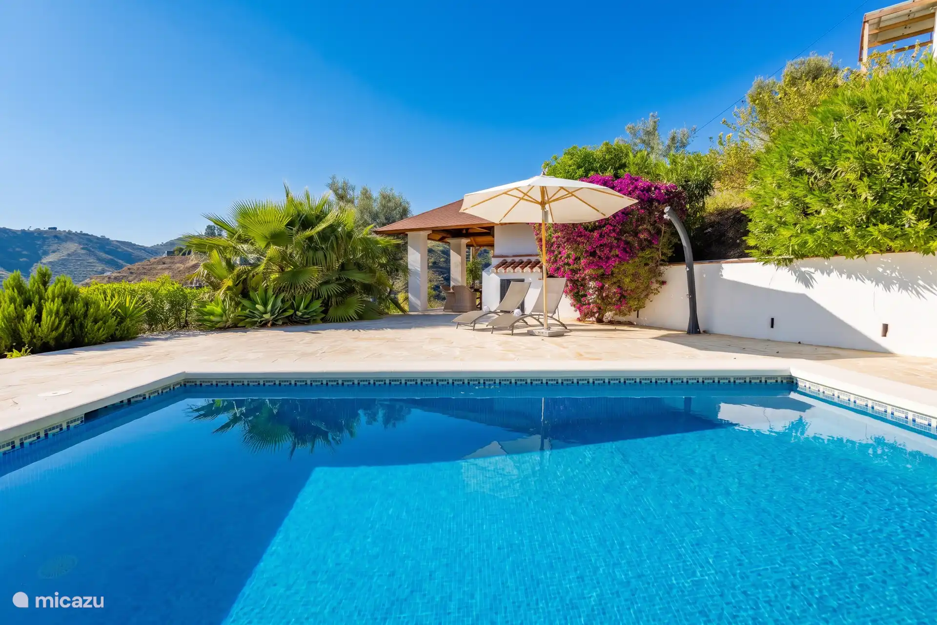 Autour de la piscine privée se trouve une grande terrasse carrelée avec des transats (6 pièces) tout autour, ainsi qu’un parasol et une douche extérieure.