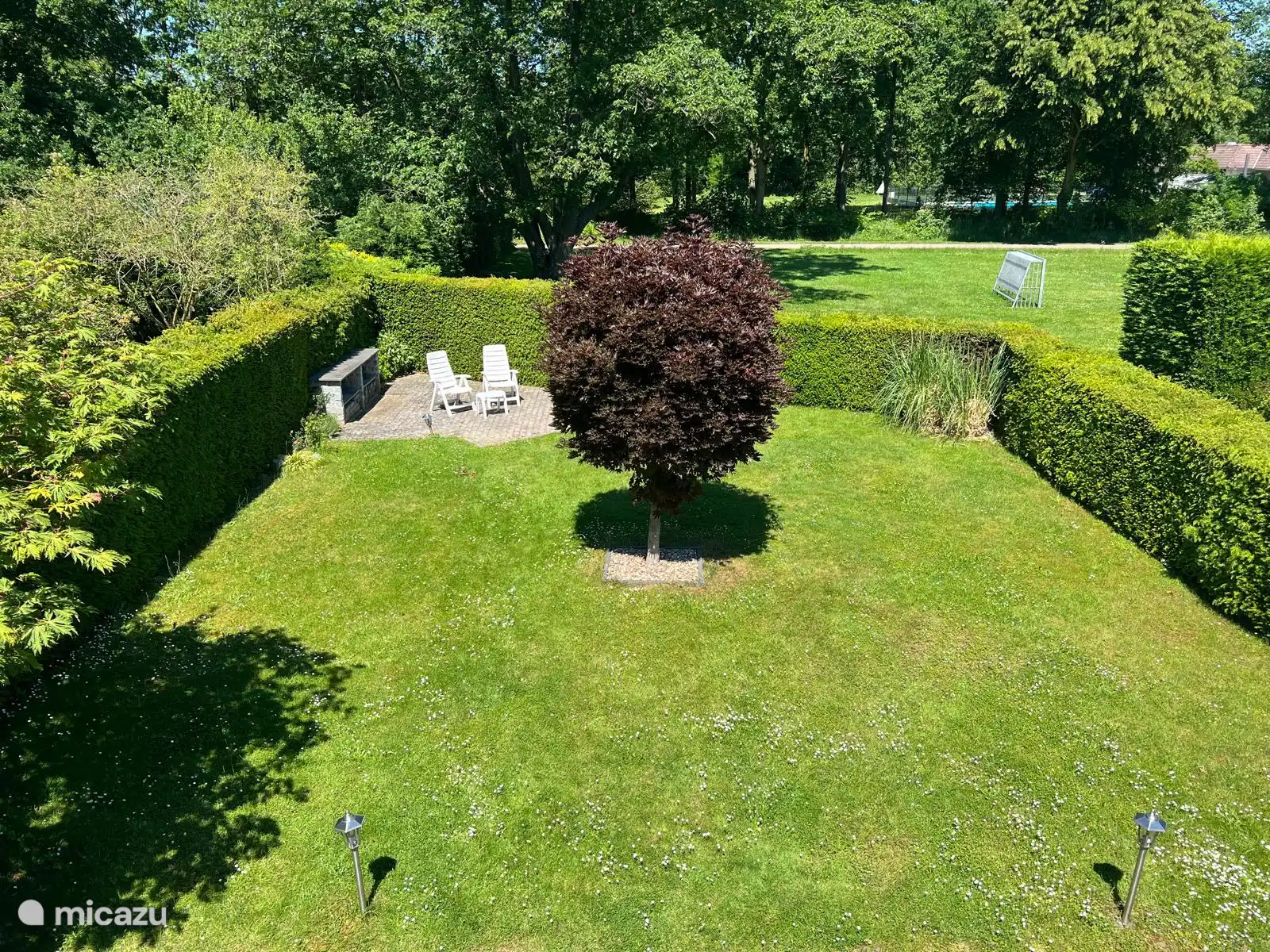 Achtertuin met aangrenzend het voetbal/sportveld en daarachter zicht op het buitenzwembad.