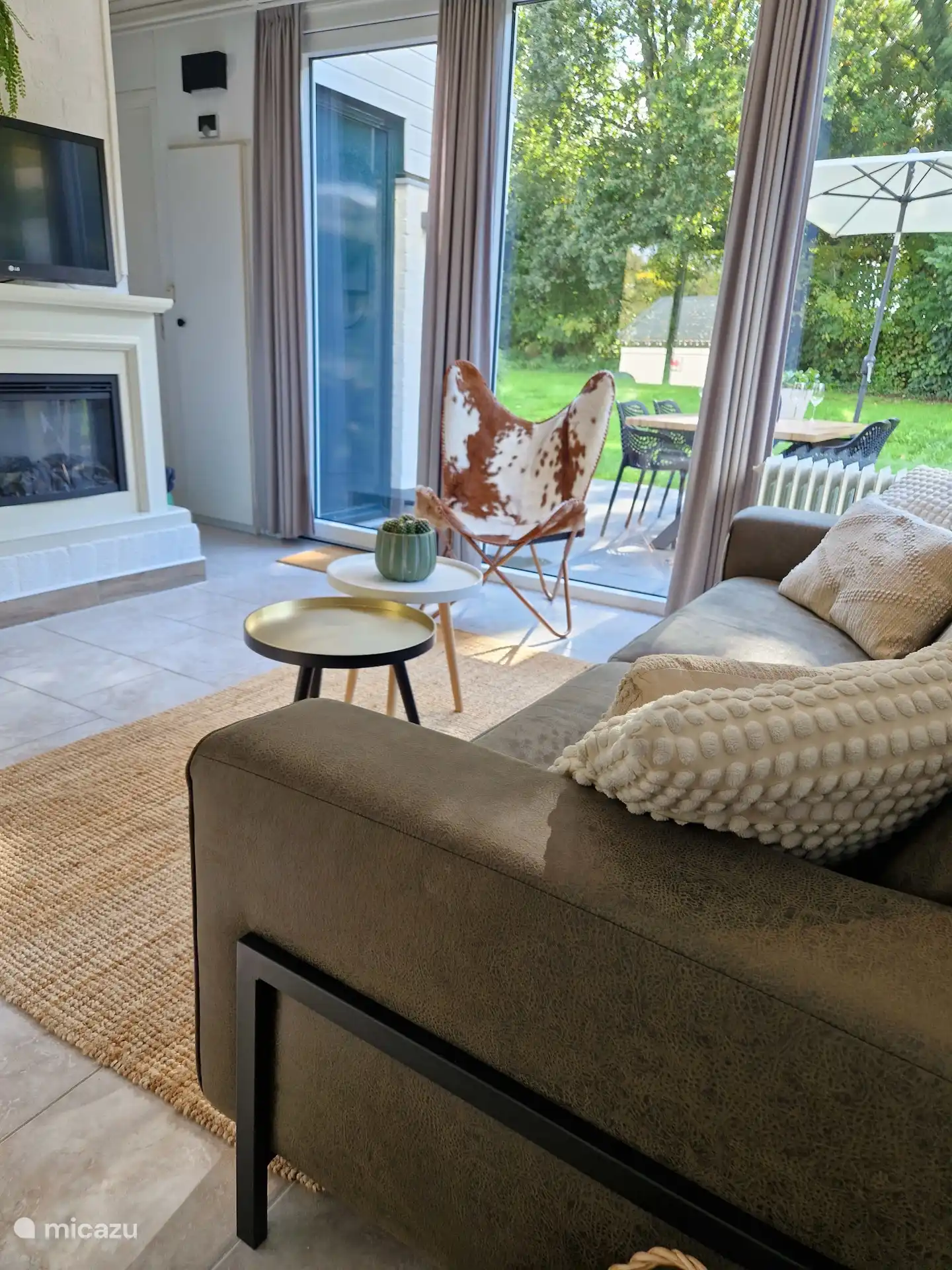 Wohnzimmer mit Kamin, Fernseher, bequemem Sofa und zwei Sesseln.