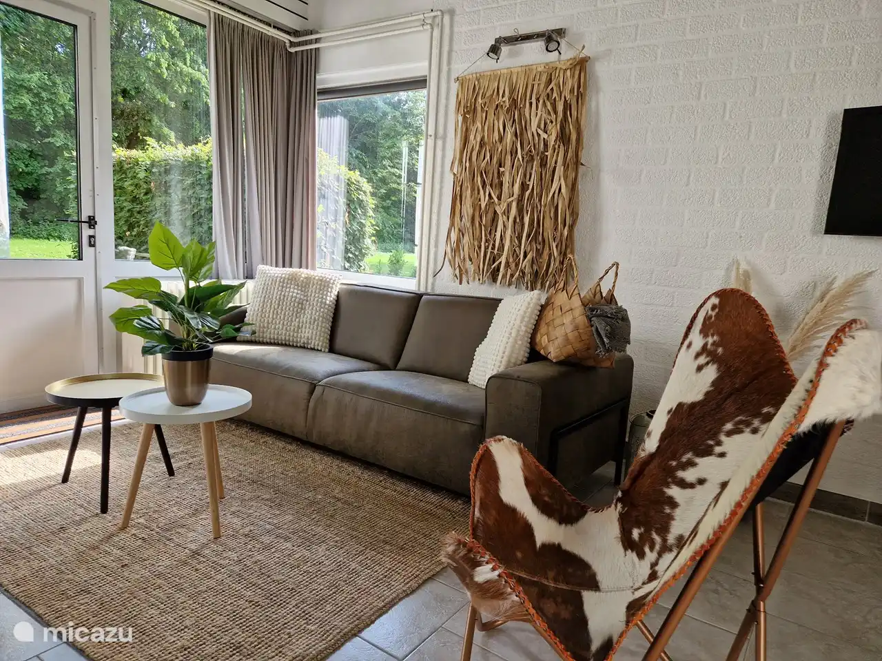 Bequeme 4-Personen-Sitzgruppe mit 3-Sitzer-Sofa und separatem Designer-Sessel. Mit Blick auf den ruhigen und grünen Garten.