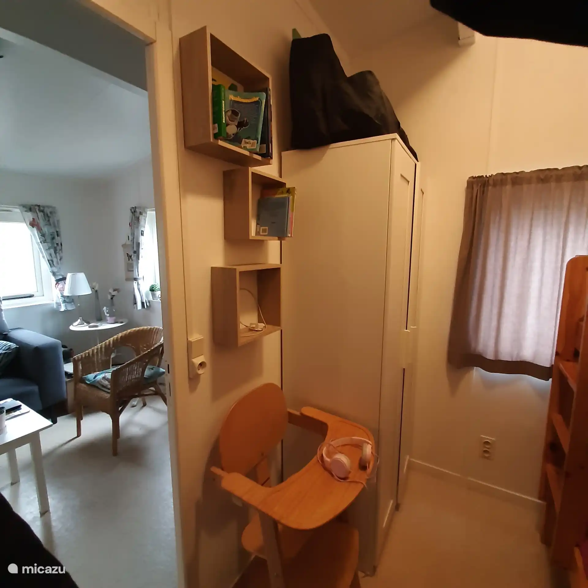 Dormitorio infantil con trona y cuna de viaje encima del armario