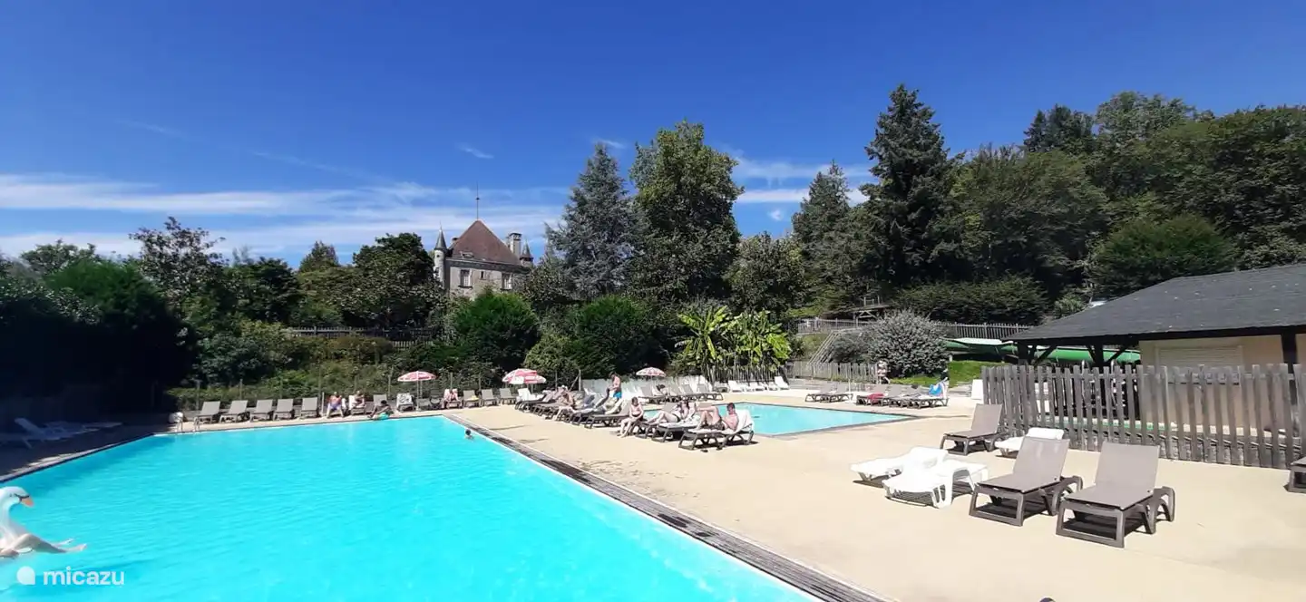 2 piscinas con muchas tumbonas y castillo al fondo