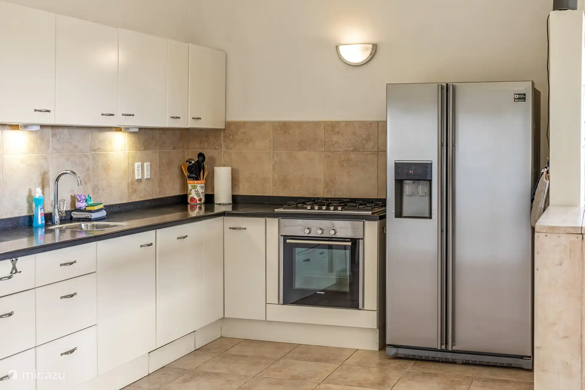 Onze keuken is uitgerust met een dubbeldeurs tropen koelkast met ijsmaker en waterdispenser, zodat je altijd kunt genieten van een verfrissend drankje.