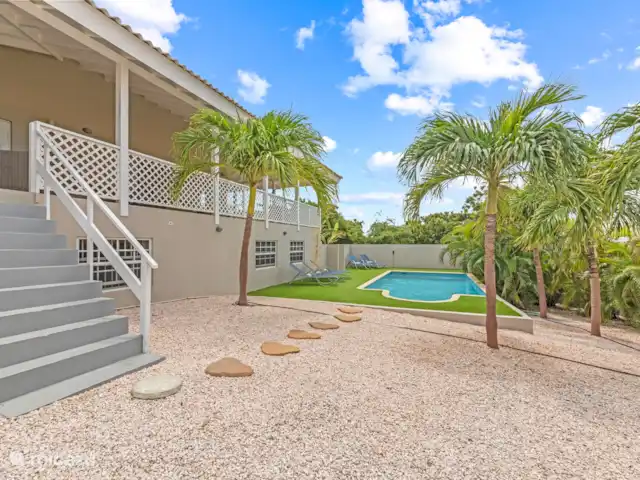 Casa Rubus | Curaçao, Banda Ariba (est), Vista Royal - villa Les escaliers de la terrasse mènent au jardin verdoyant avec grande piscine. Ici, vous pourrez vous détendre, vous rafraîchir ou profiter du calme et de l’espace qui vous entourent. Le jardin est entouré d’une végétation luxuriante et offre beaucoup d’intimité, vous pouvez donc profiter de votre séjour sans être dérangé.