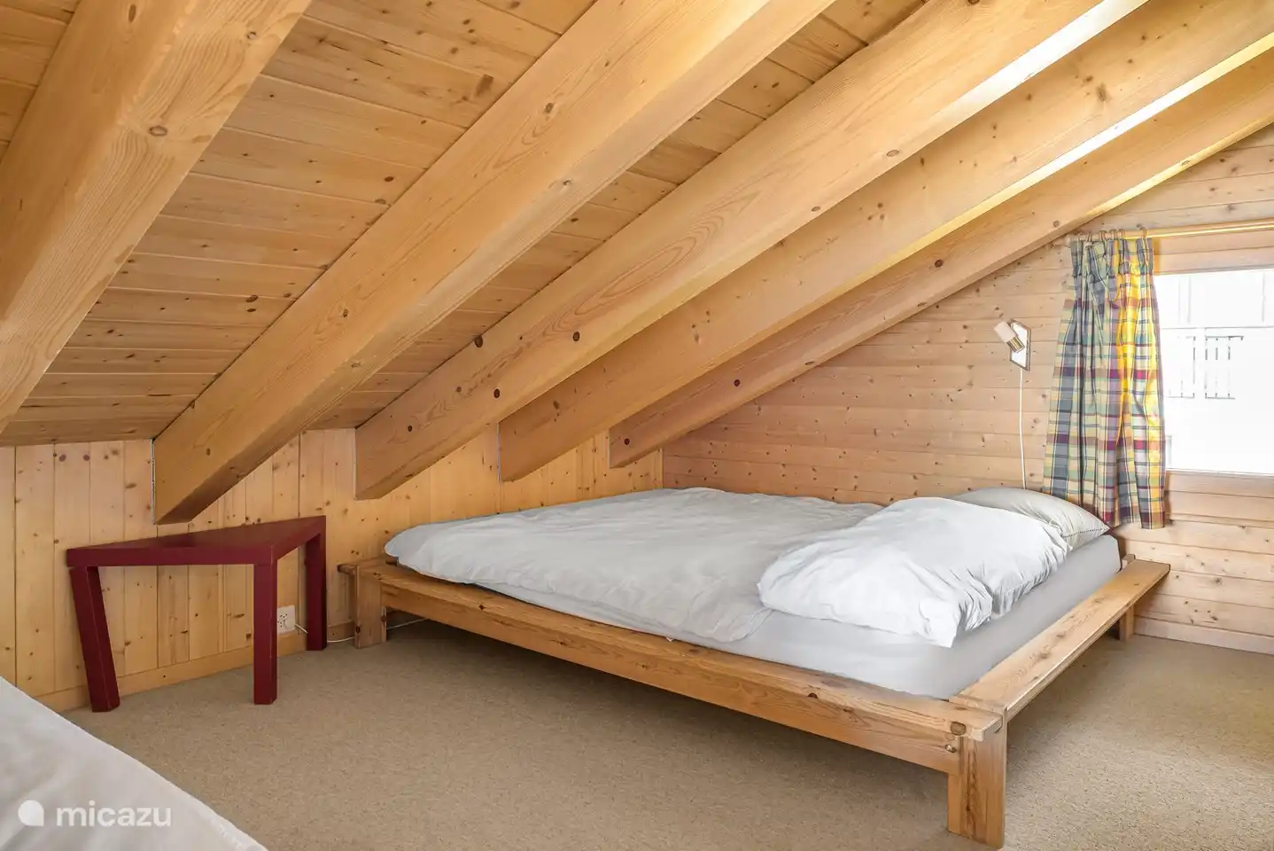 Open sleeping gallery in the sloping roof, with a French bed and an extra bed.