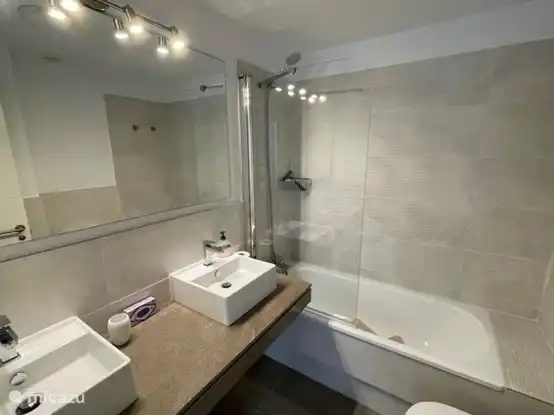 The second bathroom has a shower with bath, two sinks and toilet.