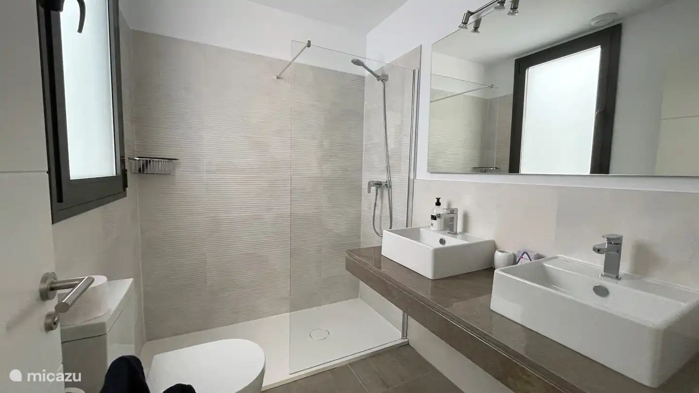 The ensuite bathroom with shower, two sinks and toilet.