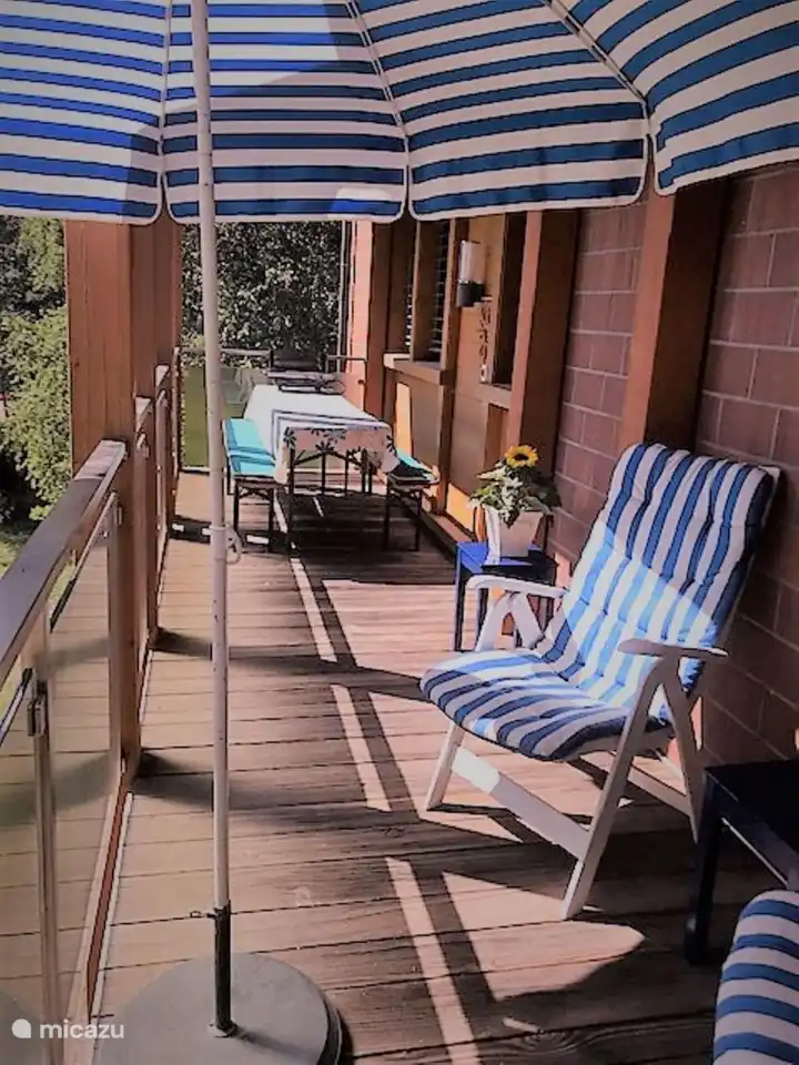 Der Balkon erstreckt sich über die gesamte Länge der Wohnung. Mit langen Tischen und Bänken und separaten Stühlen gibt es Sitzplätze für alle