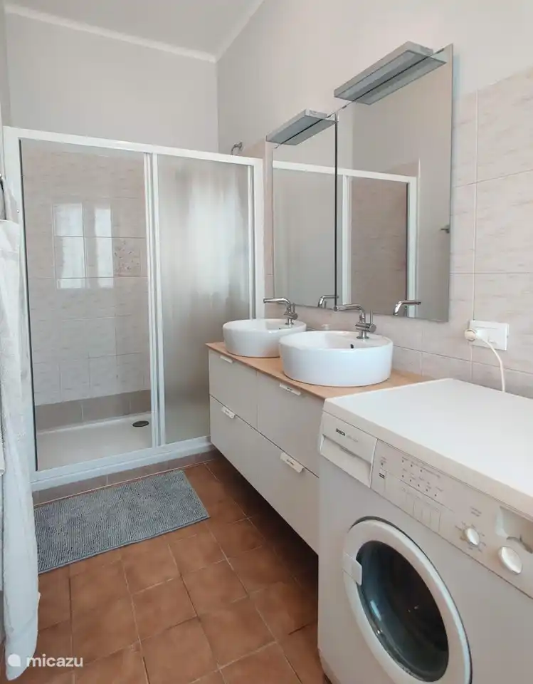 Salle de bain avec machine à laver et double vasque.