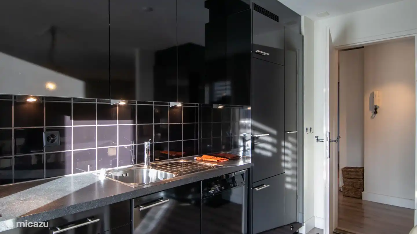 Cuisine avec cuisinière électrique, four, réfrigérateur avec congélateur, cafetière, bouilloire.